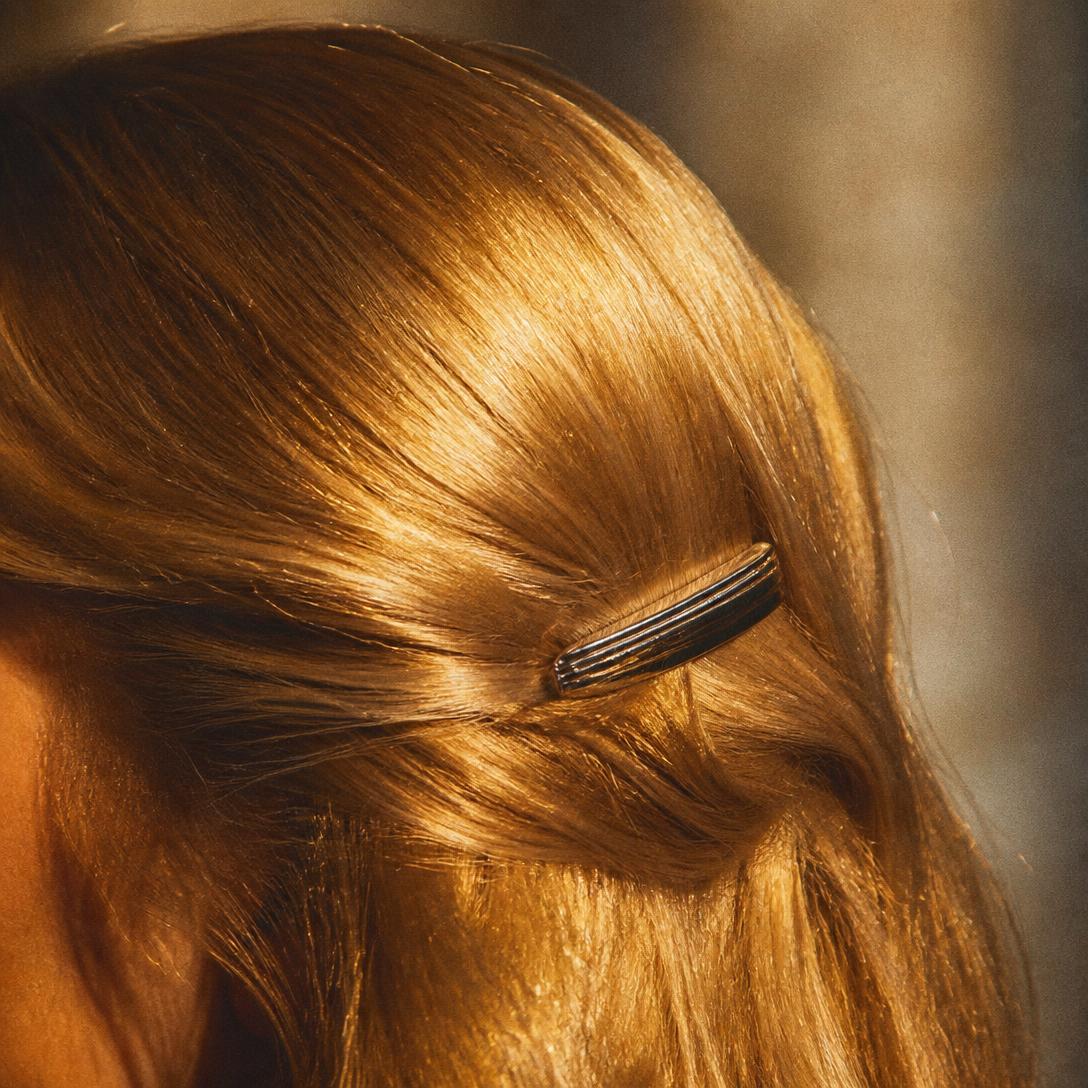 Close-up of glossy golden hair with a retro chrome clip